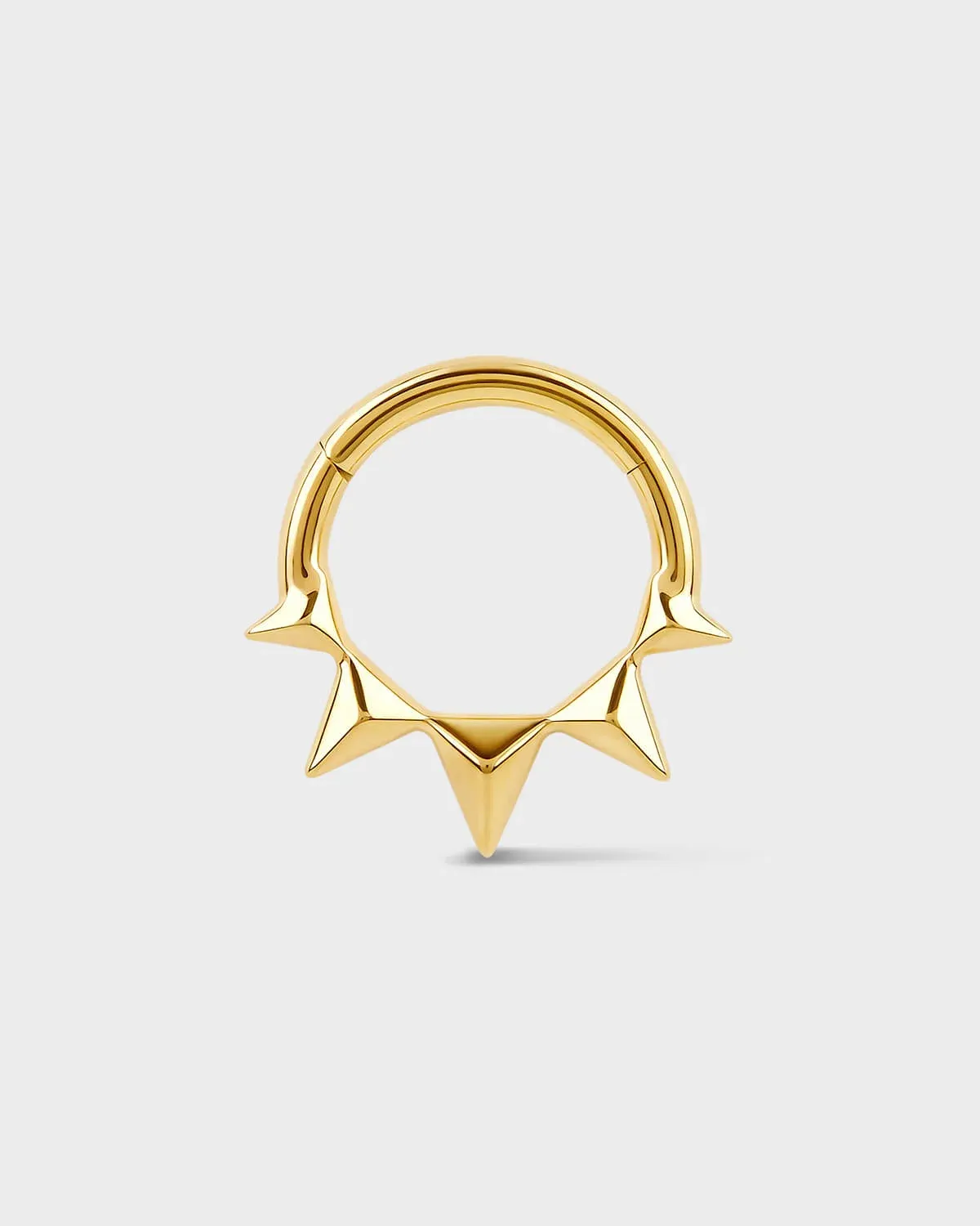 Gold septum ring with spikes on a light gray background
