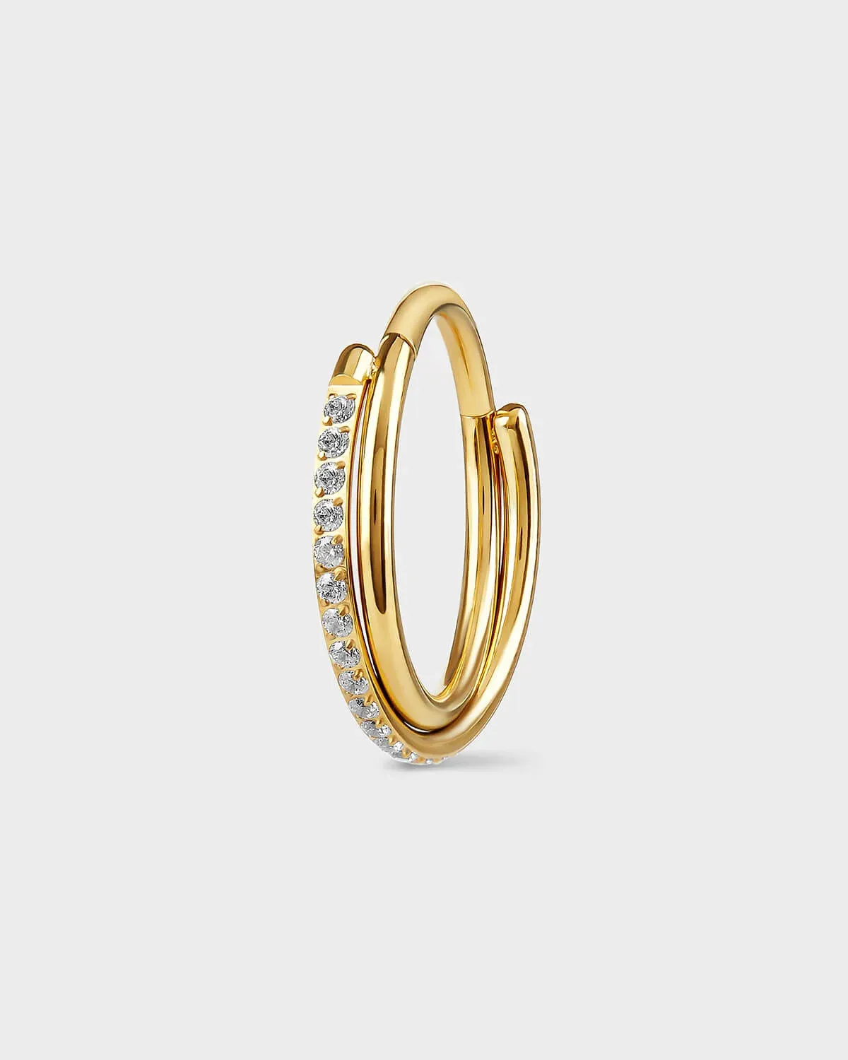 Gold titanium with double twist ring. One pave and the other plain. Clear gemstones. Sat on a light gray backround.