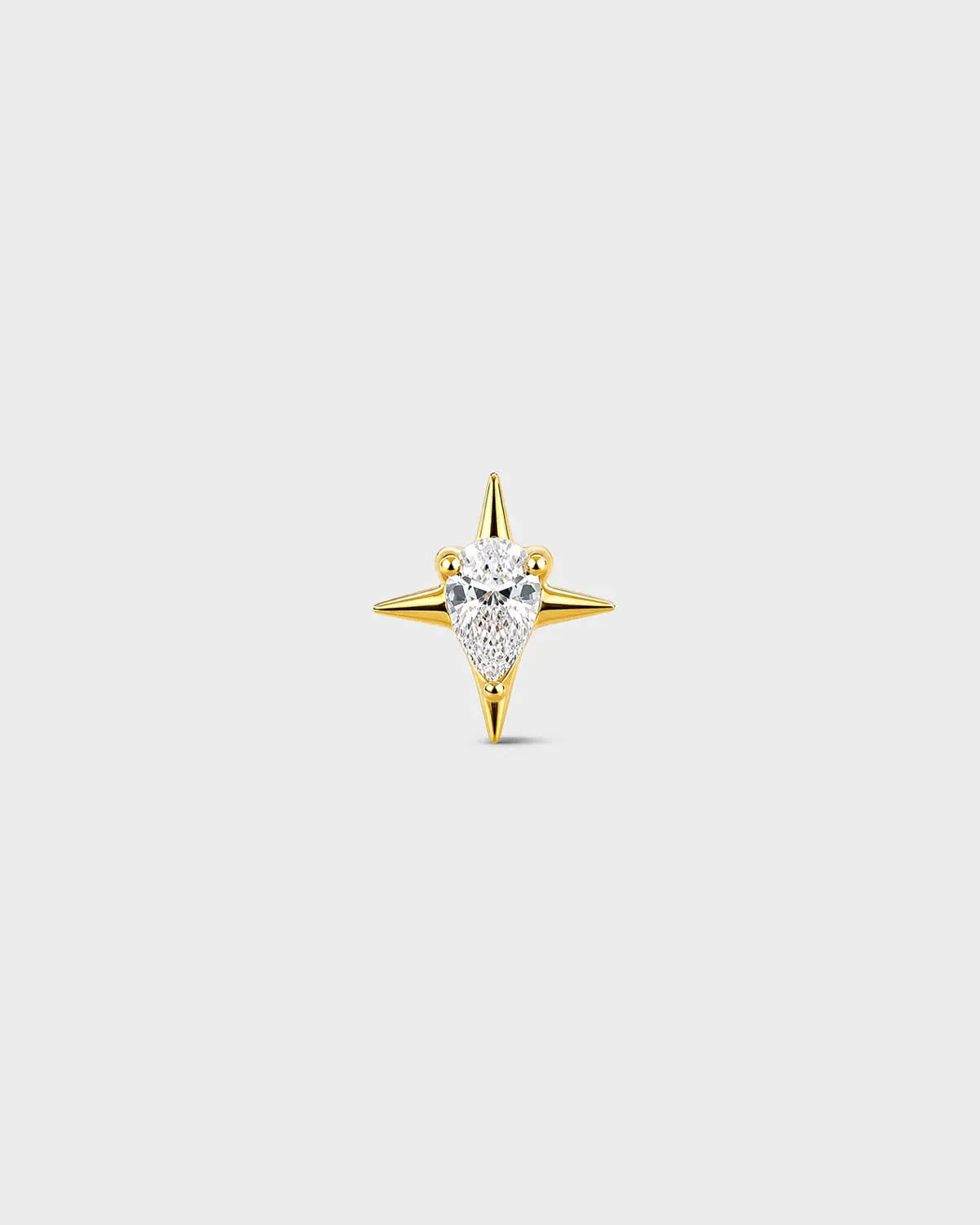 Gold titanium threadless end earring with a pear-cut clear stone set within a sculpted four-point star design. On a light grey background.