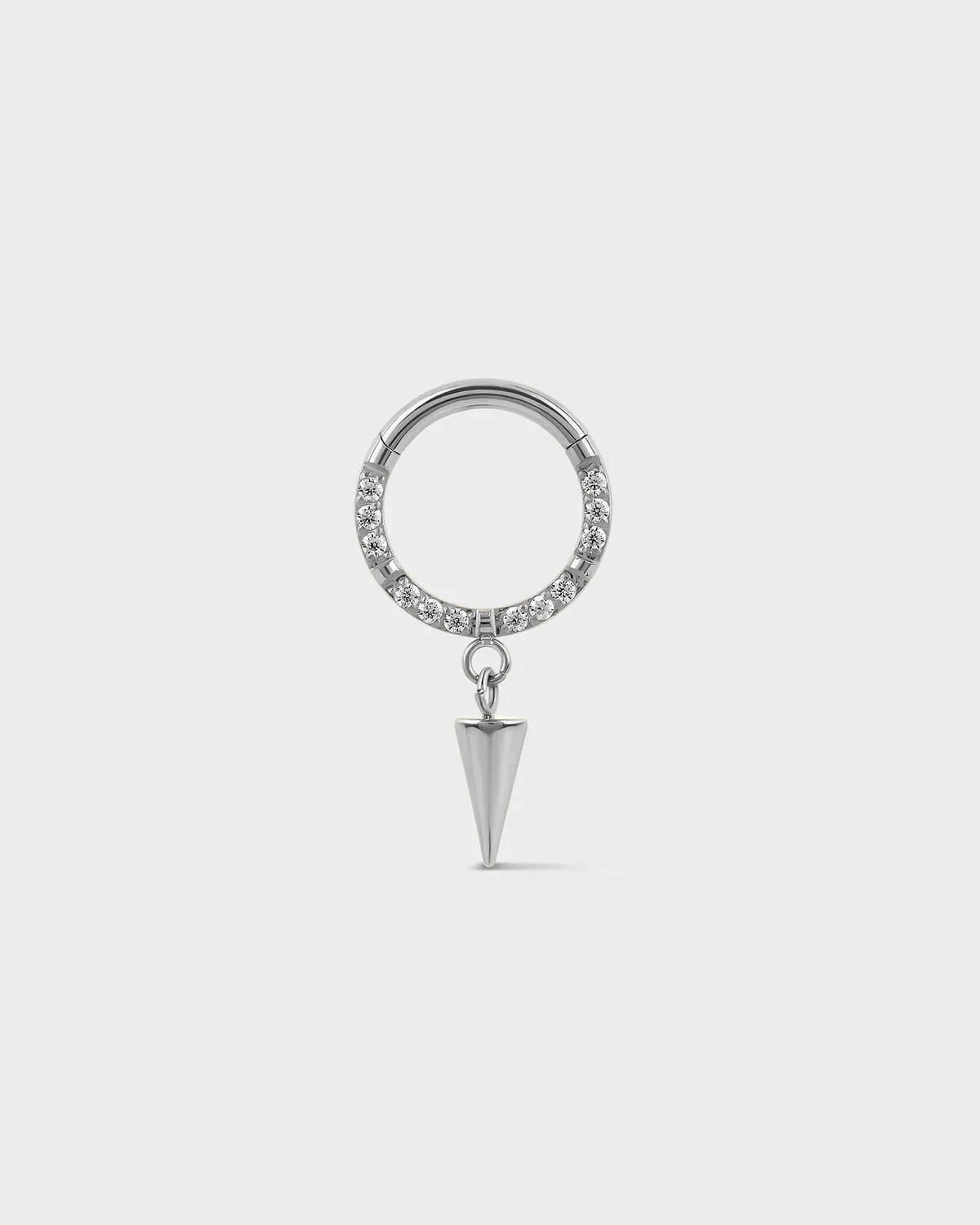 Semi pave polished silver titanium daith septum ring with dangle cone charm on a ligh gray background.