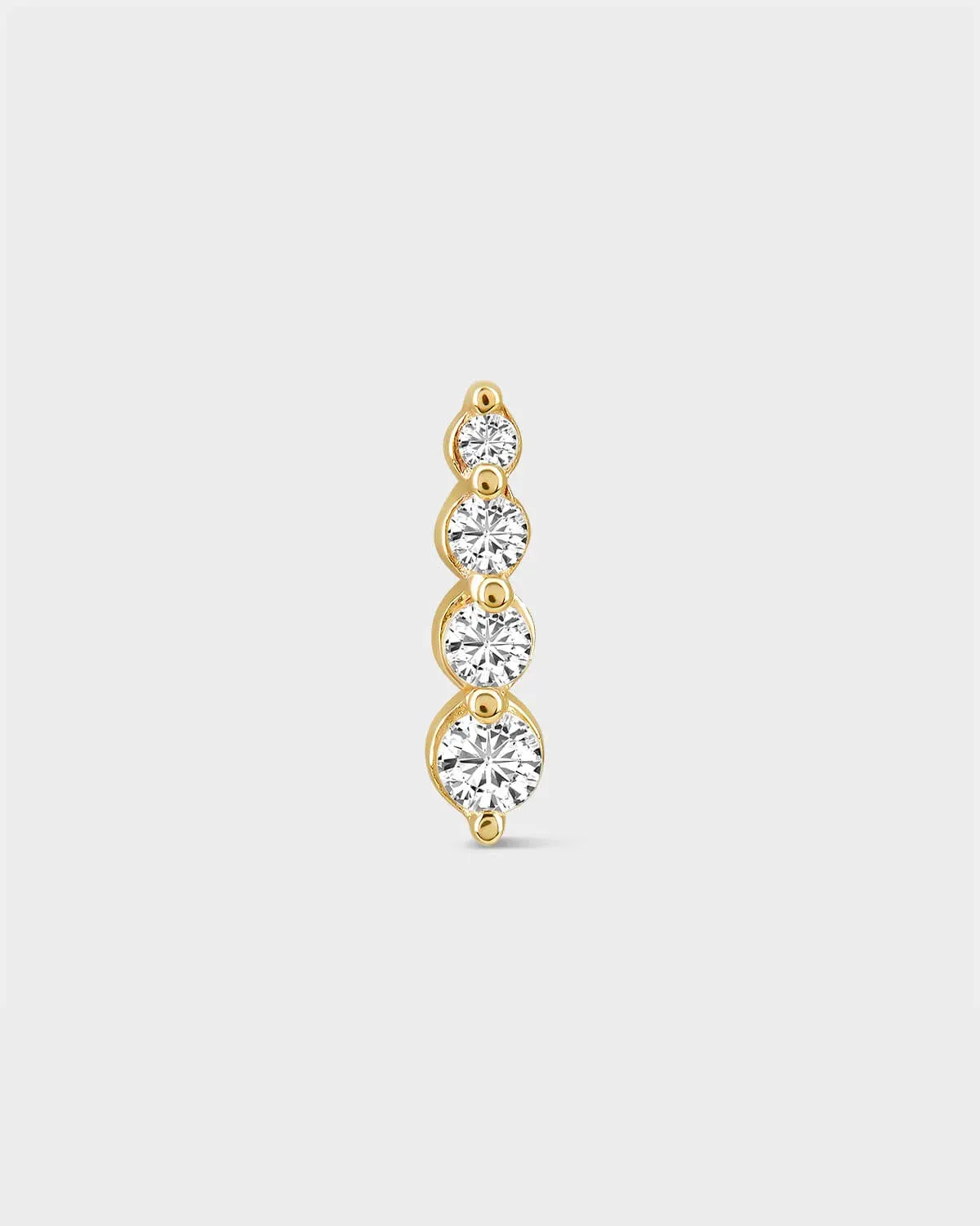 Gold earring with four clear gemstones on a light gray background