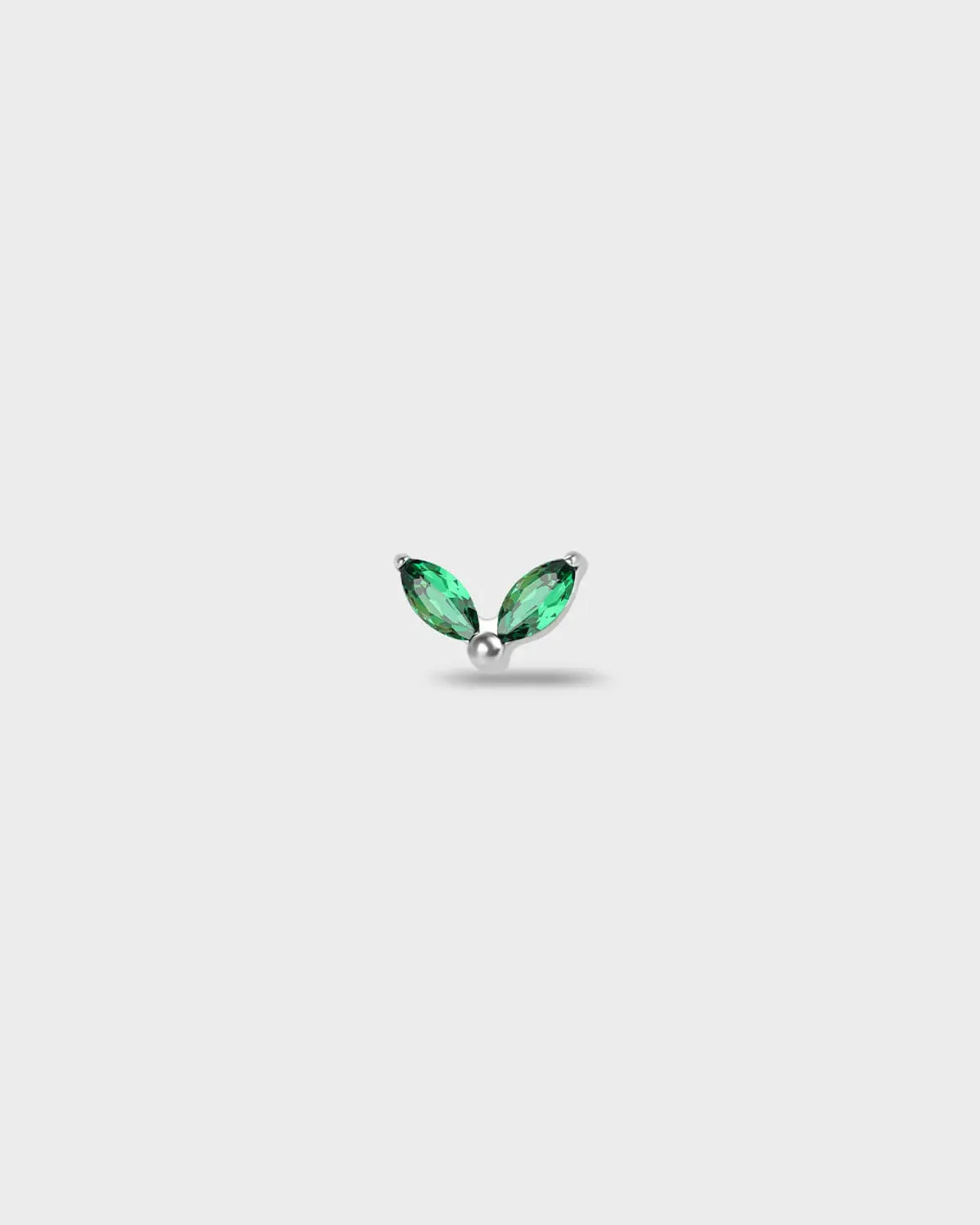 Polished titanium earring with two marquise-cut emerald green stones set in a simple leaf-style arrangement, on a light rgray background.