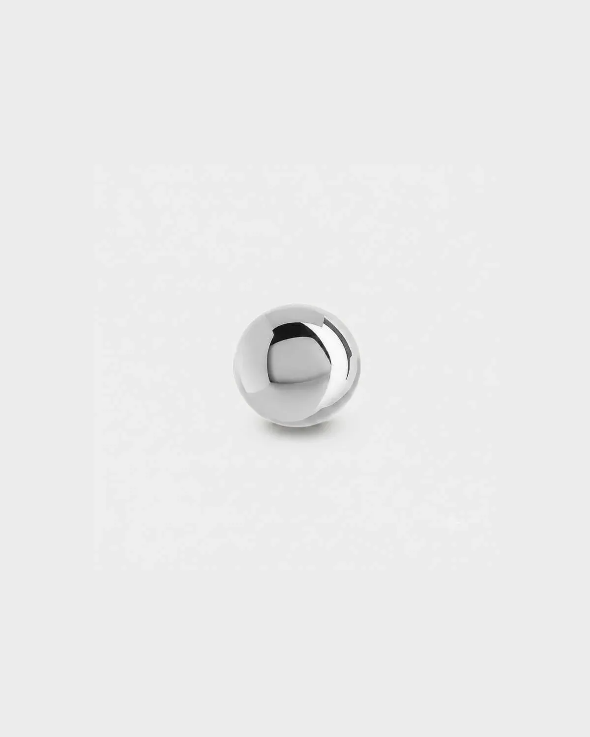 Plain polished silver titanium ball for piercing jewellery on a light grey background