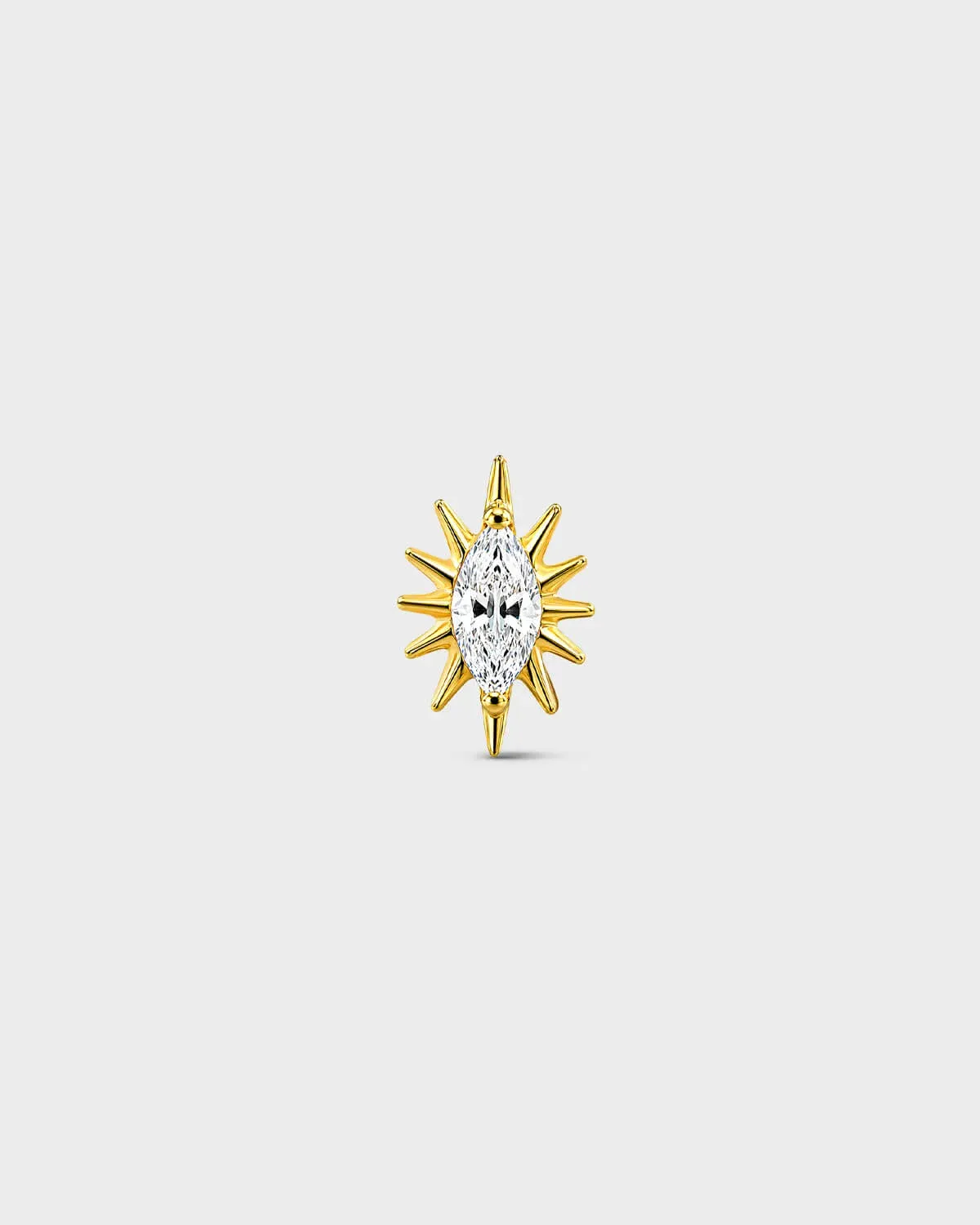 Gold titanium threadless end earring with a marquise-cut clear stone set within a sculpted starburst design. On a light grey background.