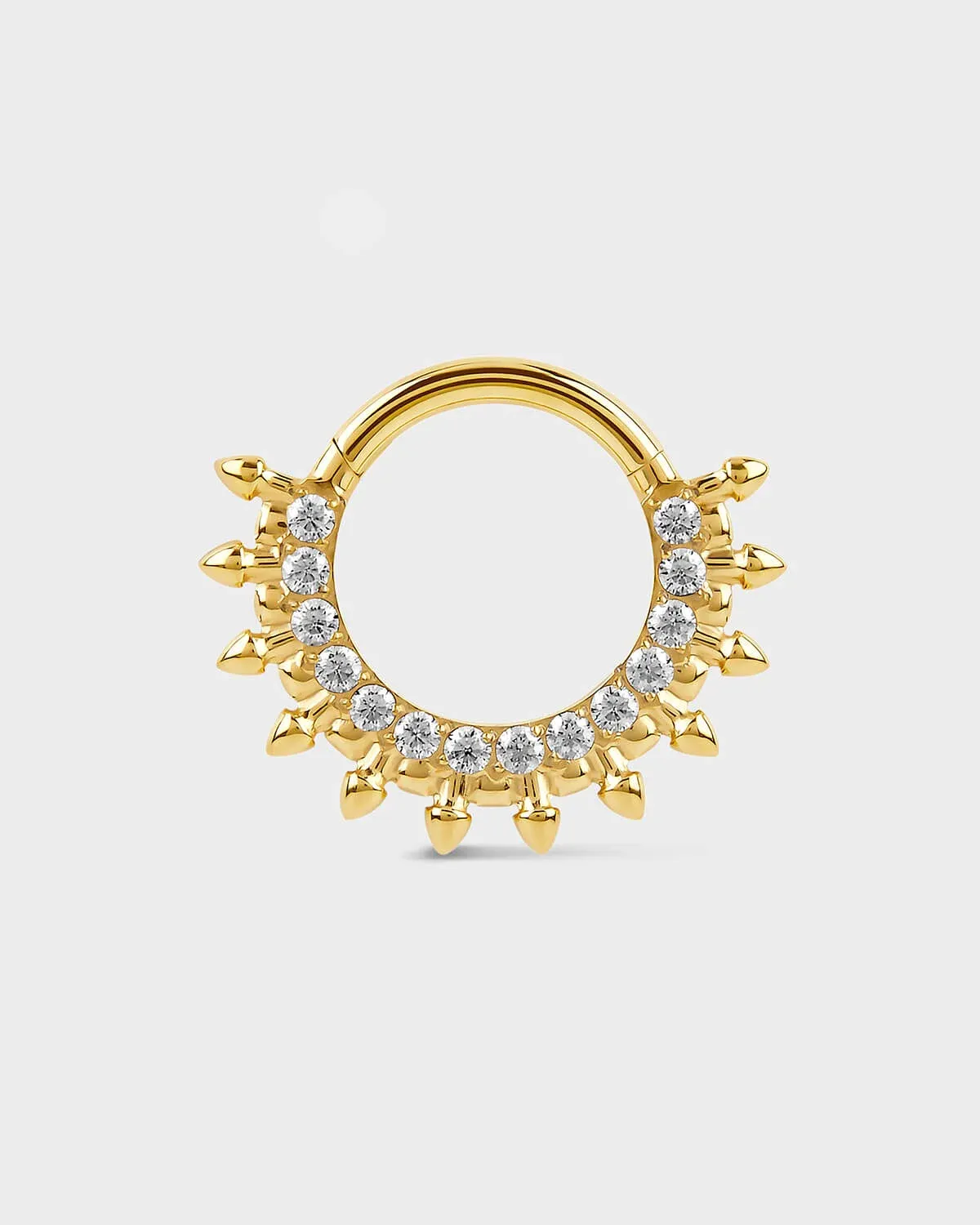 Gold septum daith ring with diamond-like stones on a light gray background