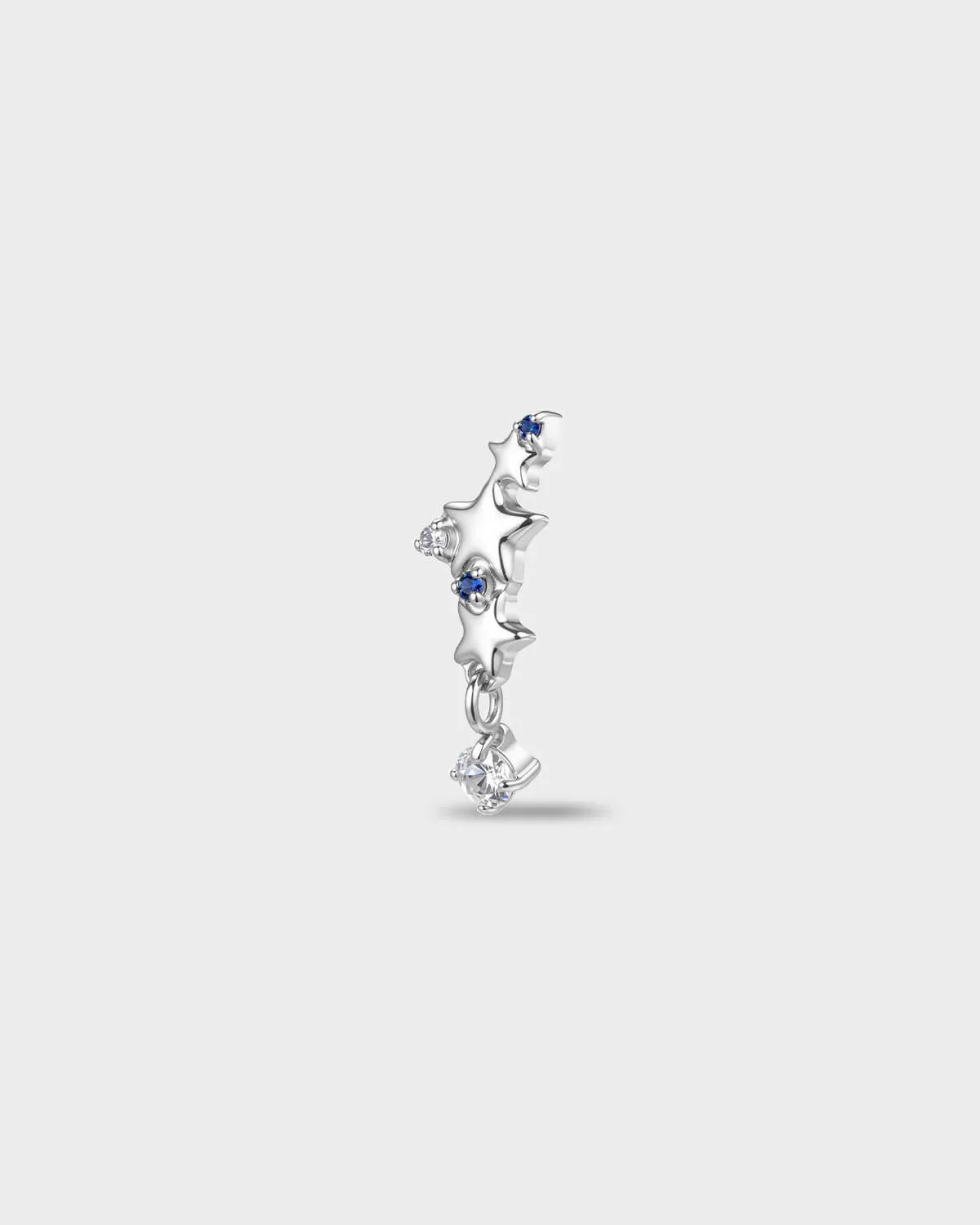Polished titanium earring with a row of star shapes set with blue and clear round-cut stones, finished with a short dangle and a clear round-cut stone, on a light gray background.