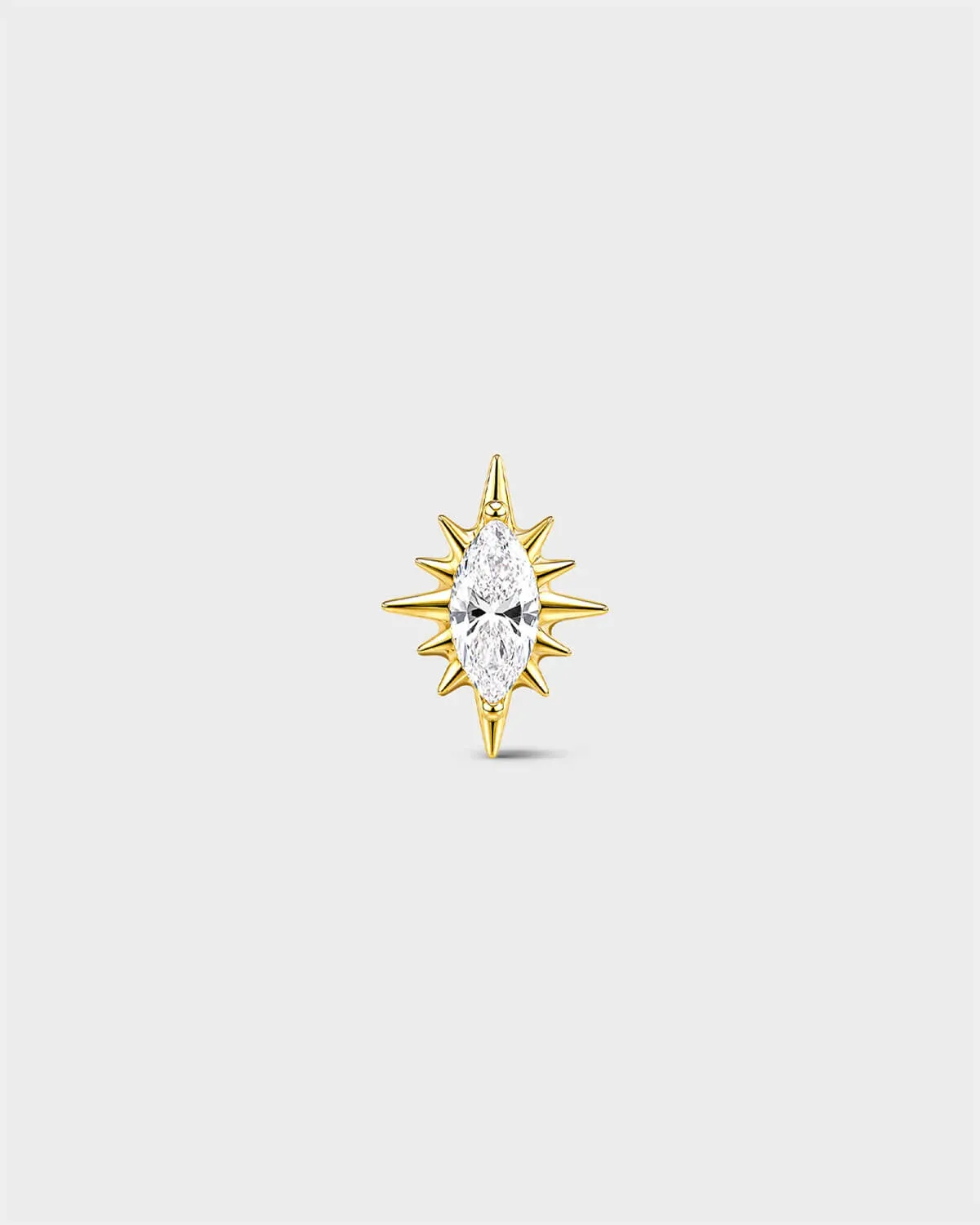Gold titanium threadless end earring with a marquise-cut clear stone set within a sculpted starburst design. On a light grey background.