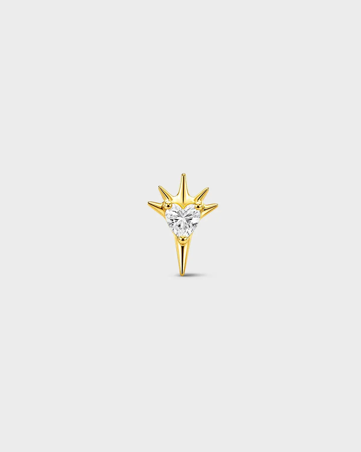 Gold titanium threadless end earring with a heart-cut clear stone set within a sculpted starburst design. On a light grey background.