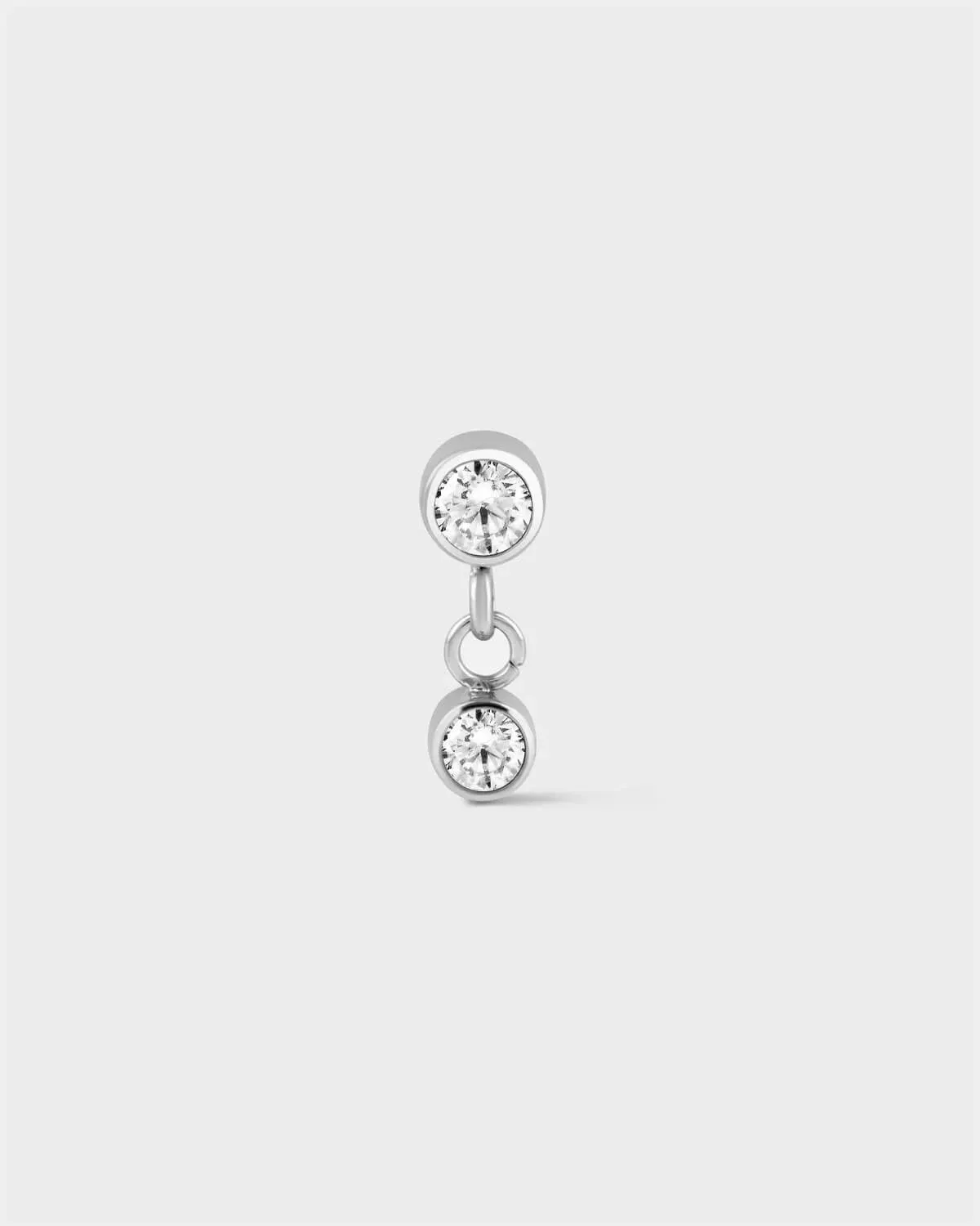 Polished titanium bezel set solitaire earring with a second smaller bezel set solitaire drop with ring connector on a light grey background.