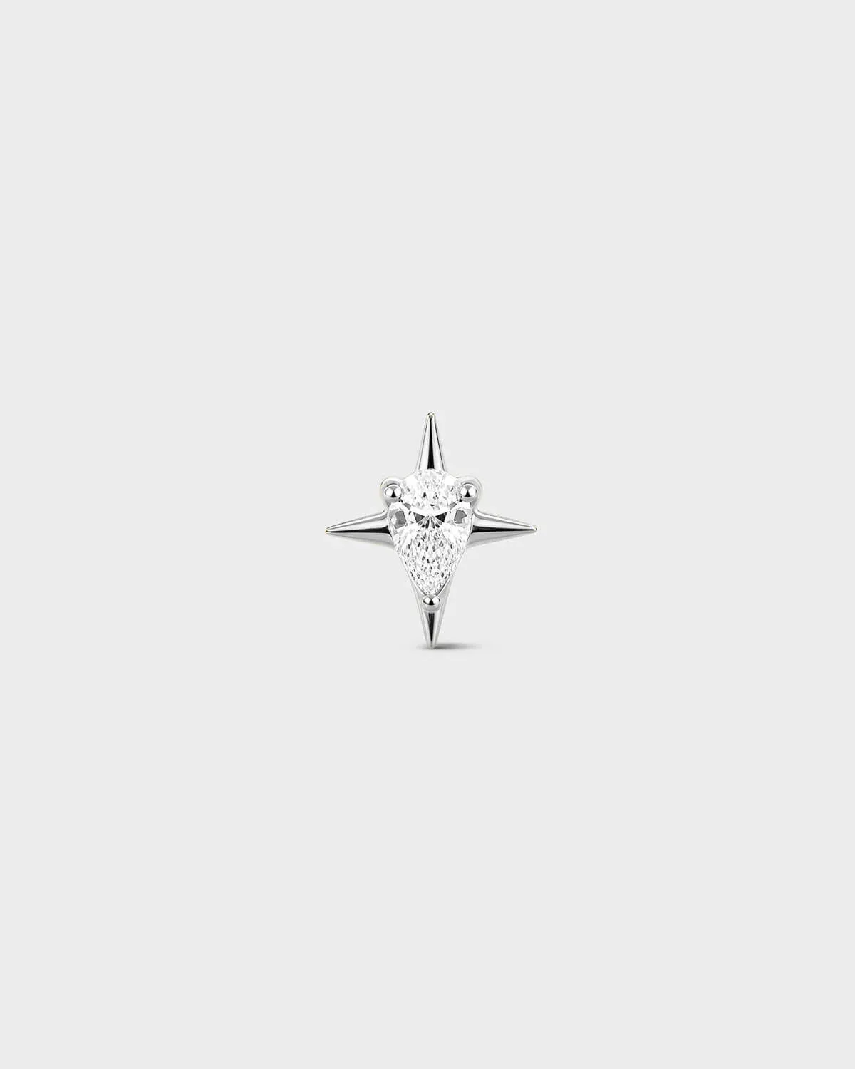 Polished silver titanium threadless end earring with a pear-cut clear stone set within a sculpted four-point star design. On a light grey background.