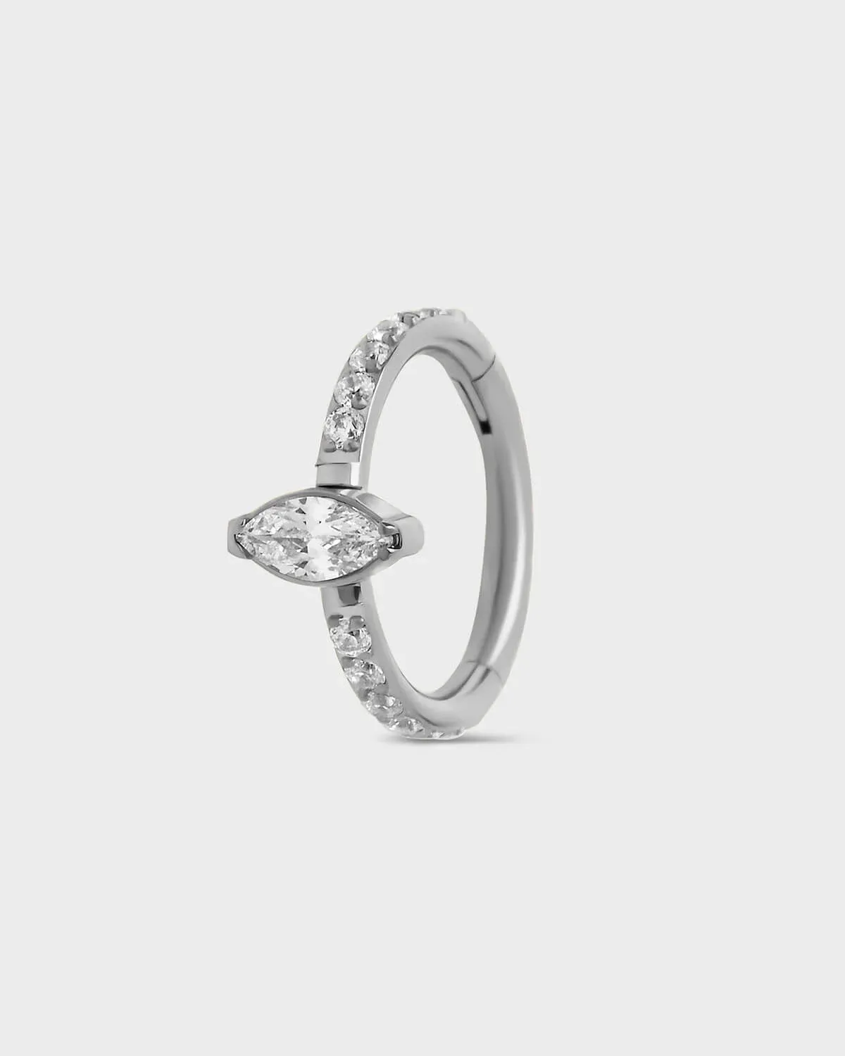Polished silver titanium pave hinged ring with central marquise gem sat on a light gray backround.