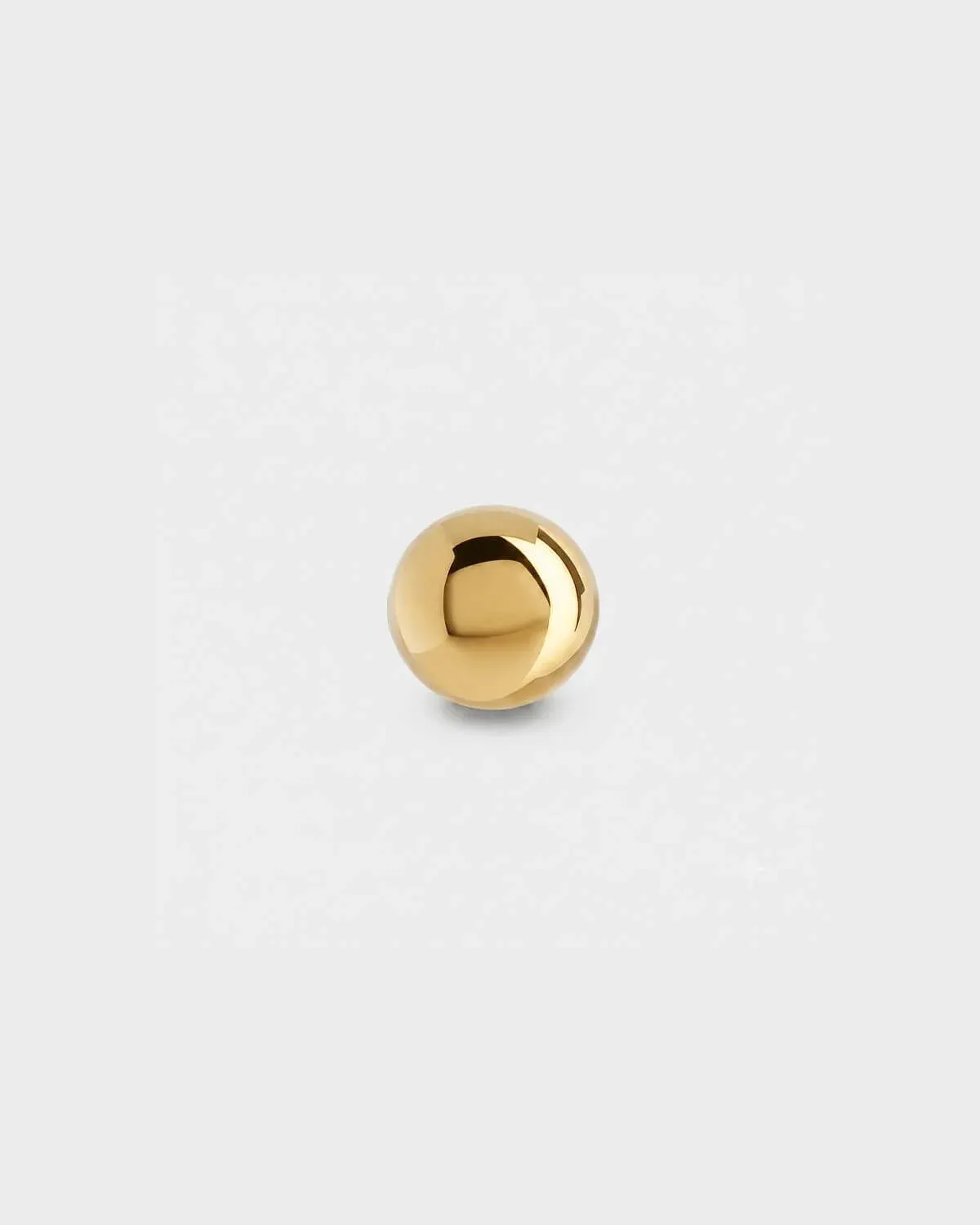 Plain gold titanium ball for piercing jewellery on a light grey background