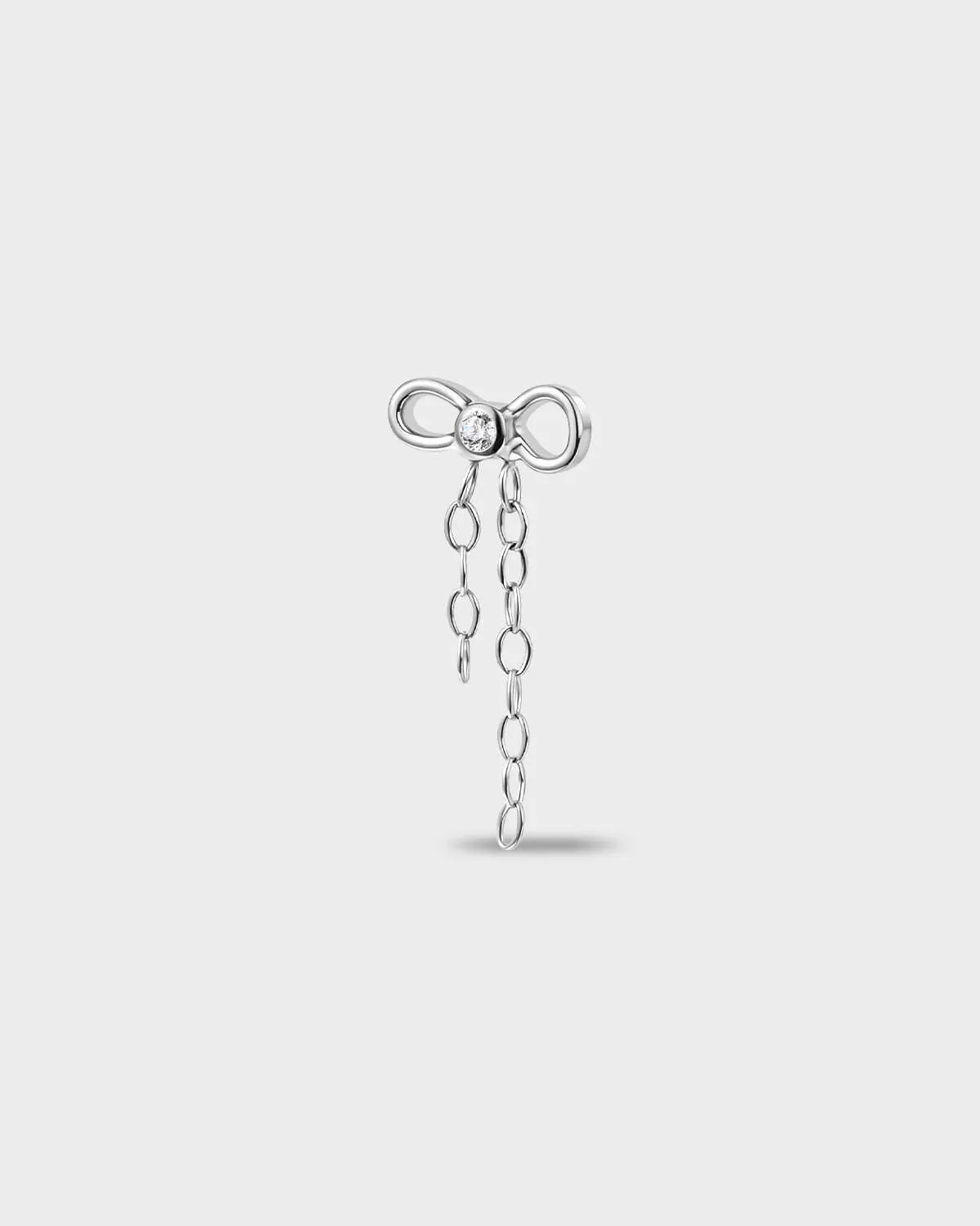 Polished titanium earring with a bow-shaped top set with a clear round stone and a double chain dangle on a light gray background.
