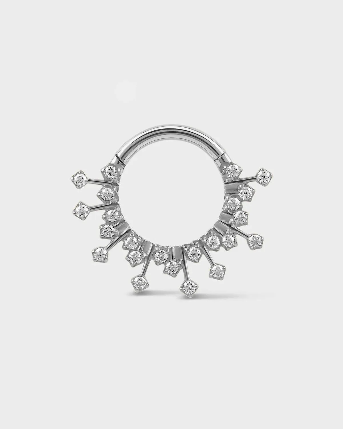 Polished silver titanium daith septum ring with small gramstones on a light gray background