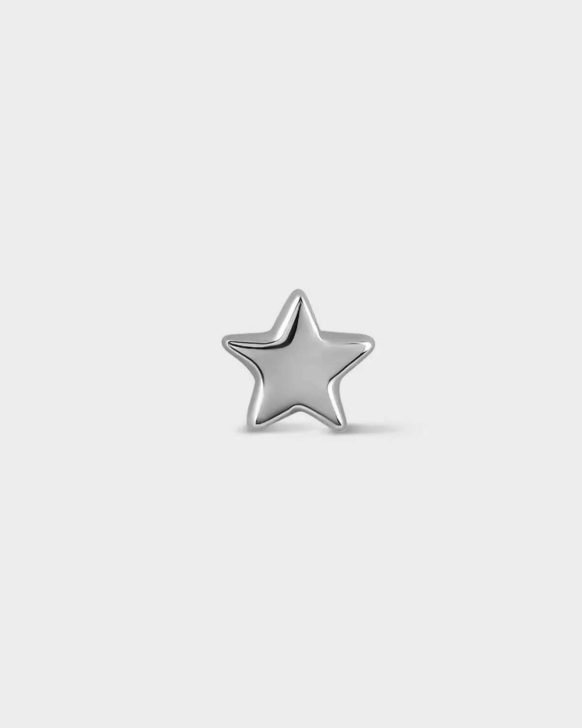 Silver star-shaped earring on a light gray background