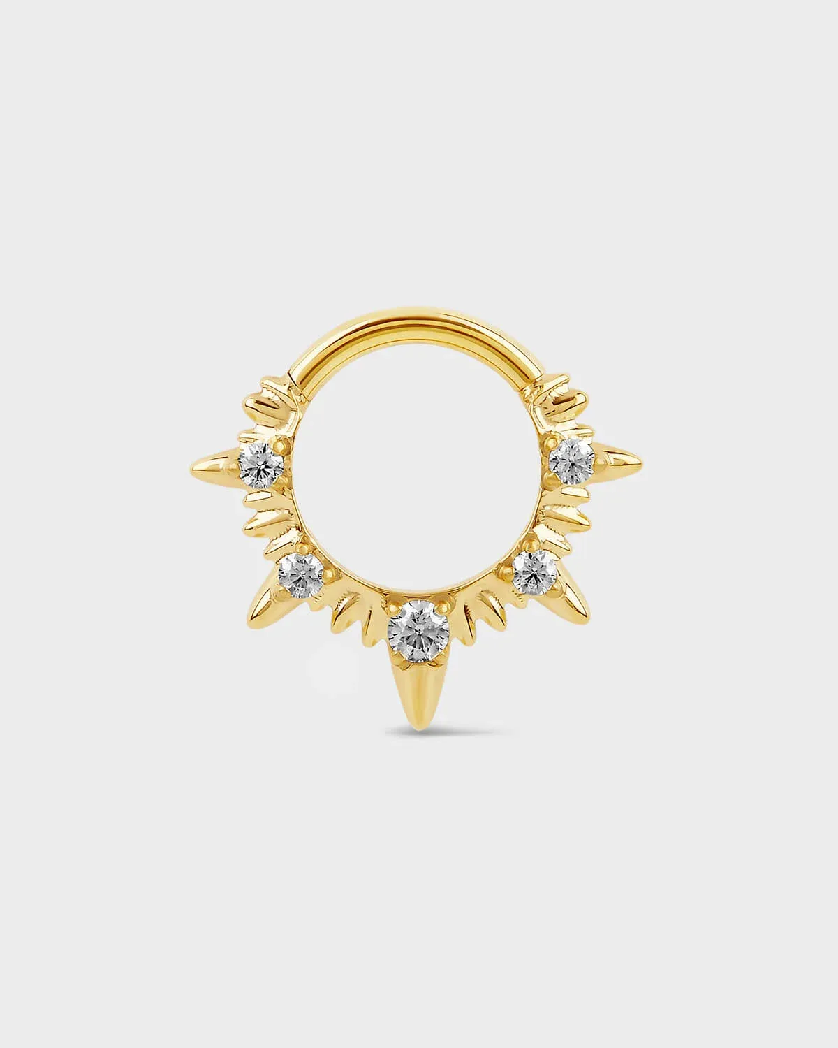 Gold septum ring with diamond-like stones on a light gray background