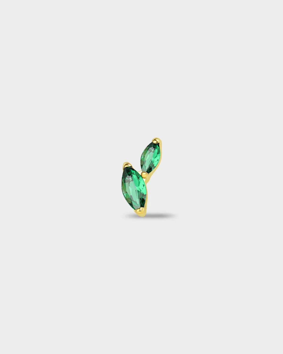Gold titanium earring with two marquise-cut emerald green stones set in a curved vertical arrangement on a light gray background.