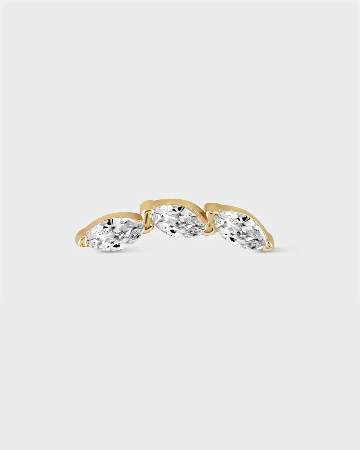 Gold earring with three clear gemstones on a light gray background