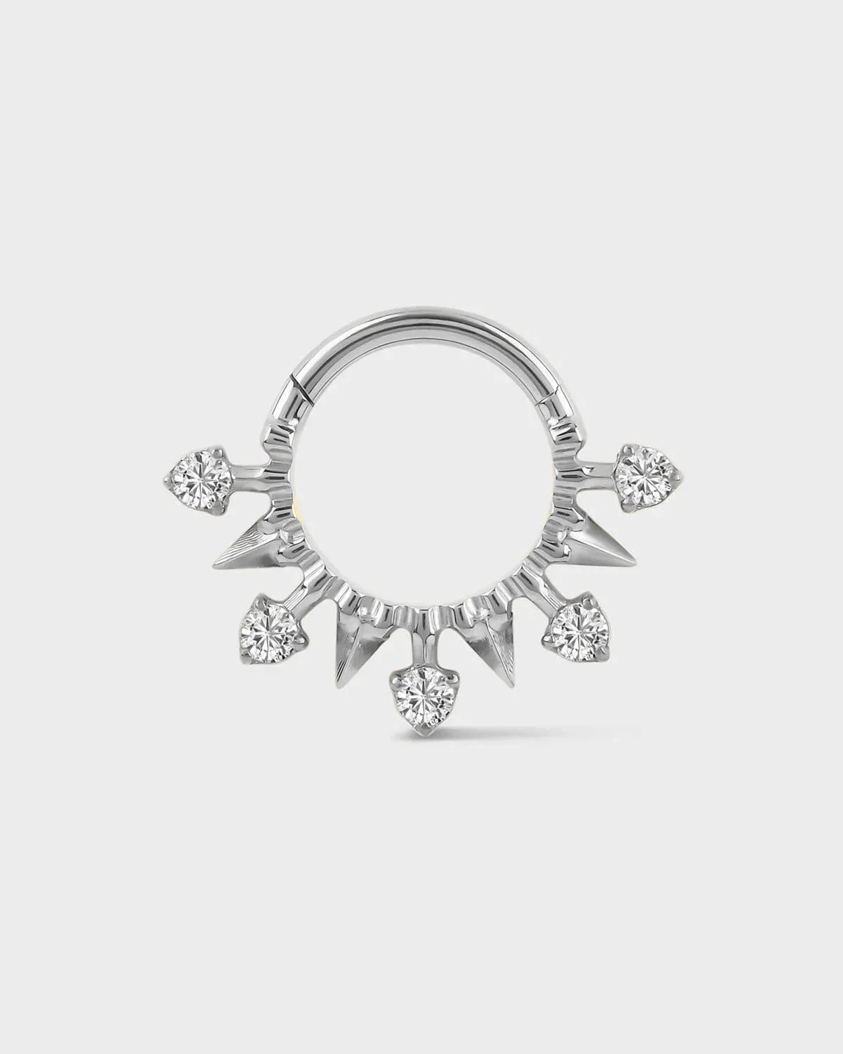 Polished silver titanium daith or septum ring with alternating spikes and solitaires on a light gray background.