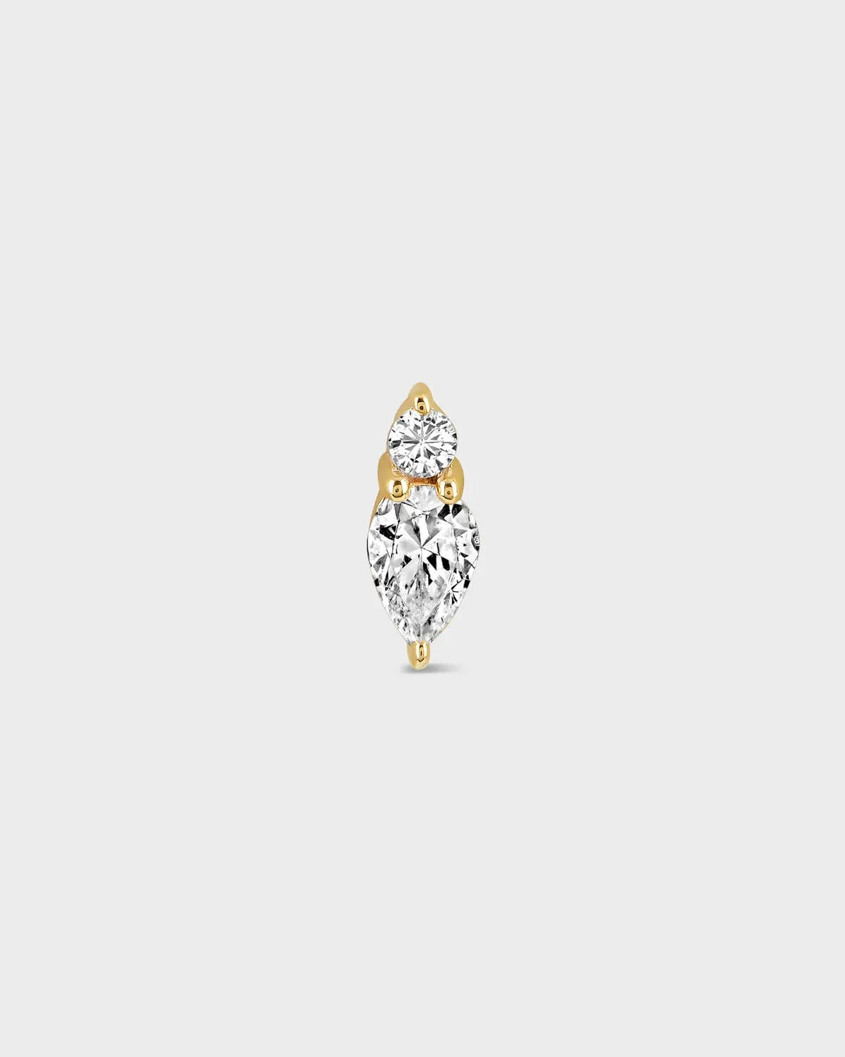 Gold and diamond earring on a light gray background