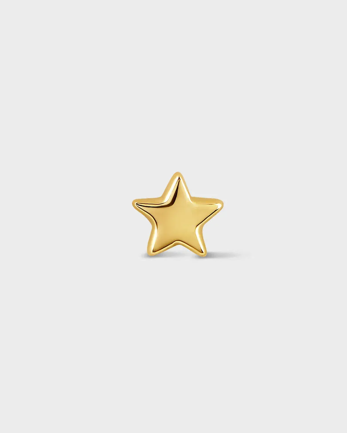 Gold star-shaped earring on a light gray background