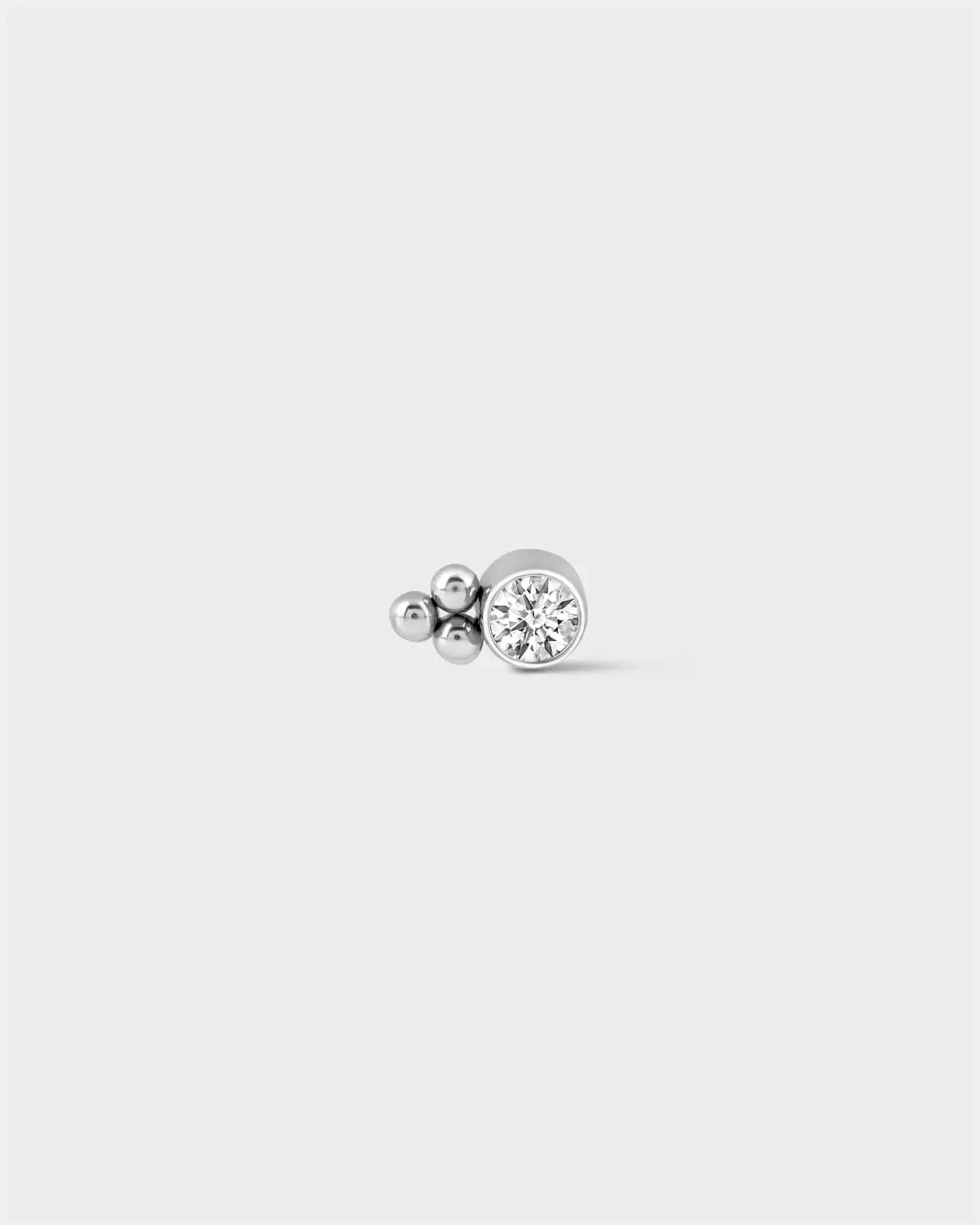 Polished silver titanium bezel set solitaire earring with 3 beads detail to one side on a light grey background.
