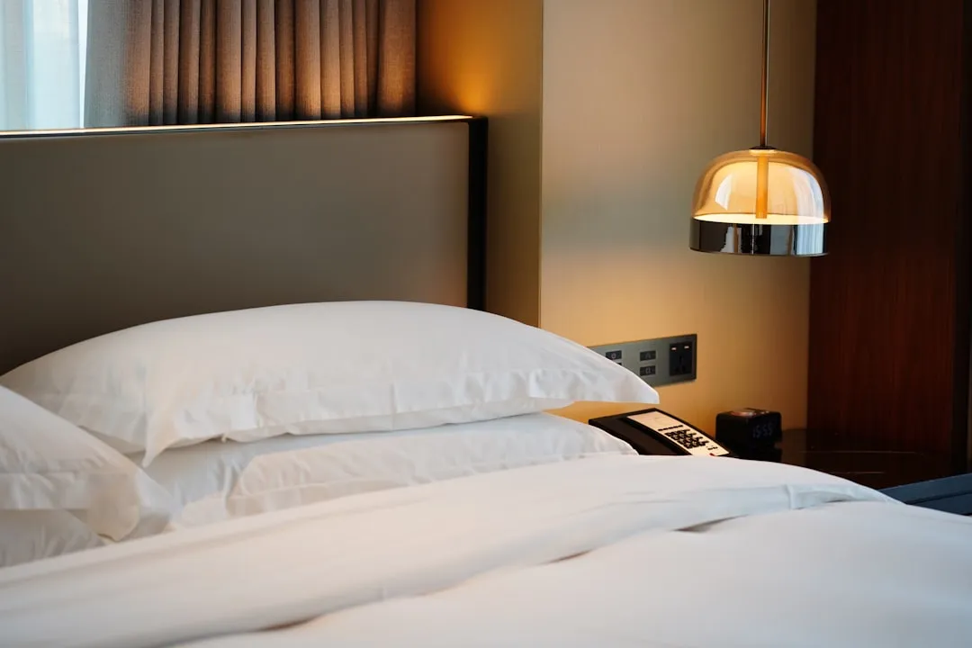 a bed with white pillows and a phone on it