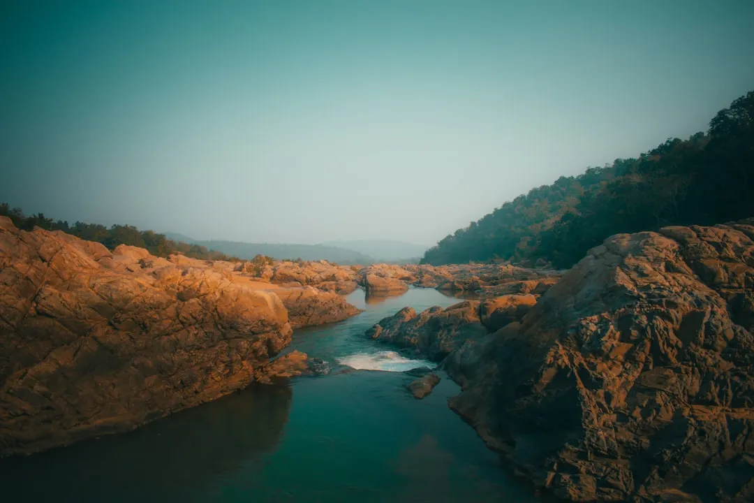 brown rocky mountain beside river during daytime