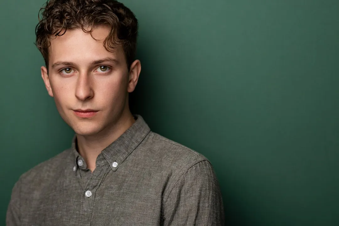 Young man with curly hair against green background