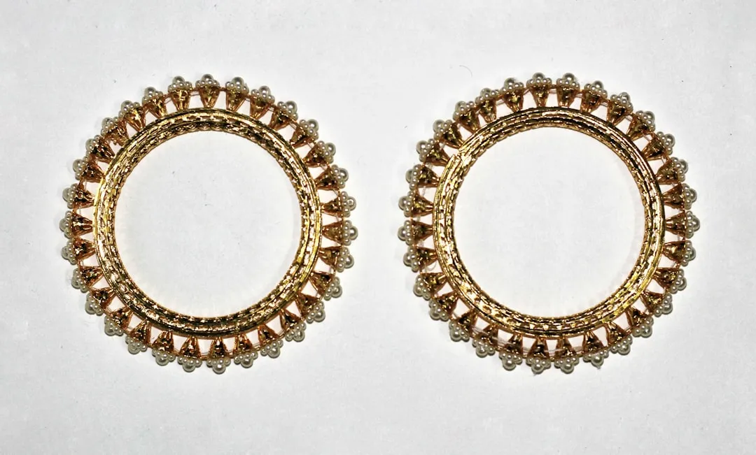A pair of gold toned earrings on a white background