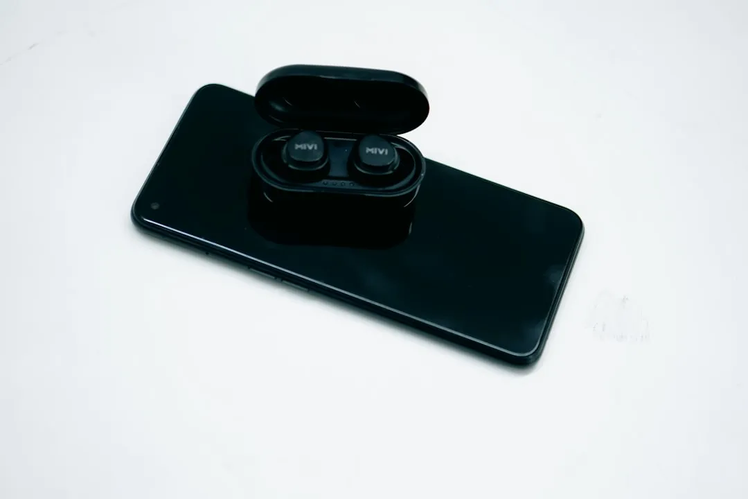 a pair of black earbuds sitting on top of a black phone