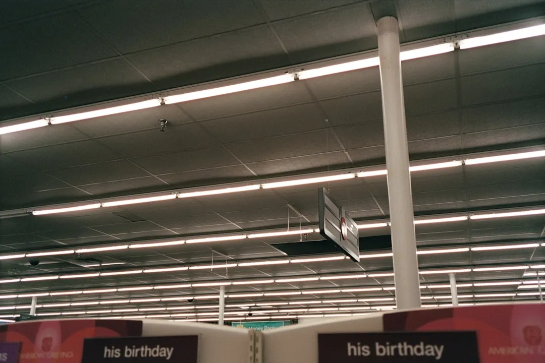 Fluorescent lights illuminate a retail store ceiling with signs.